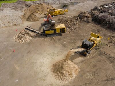 An aerial shot of multiple waste processing machines grinding and shredding wood waste