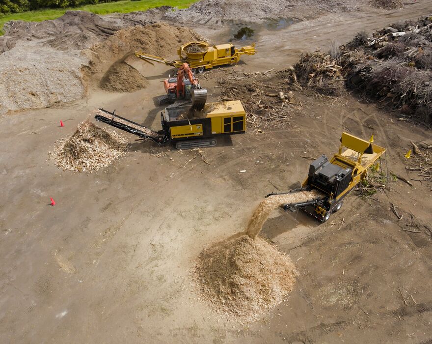 An aerial shot of multiple waste processing machines grinding and shredding wood waste