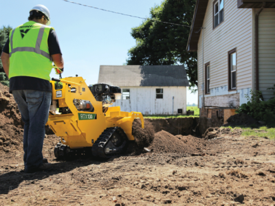 Man in a yellow reflective jacket pushes a pedestrian trencher in a residential area