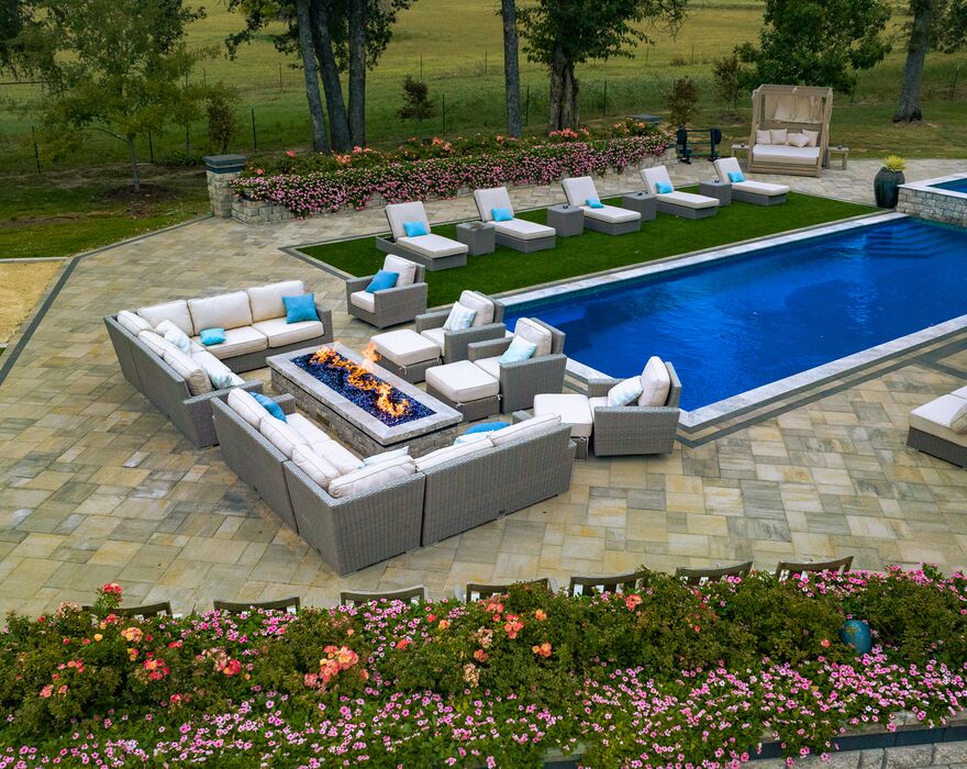 A pool with stone patio landscaping and outdoor chairs and lounges