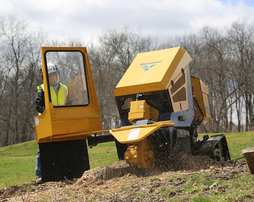 A man grinding a stump from a protective barrier