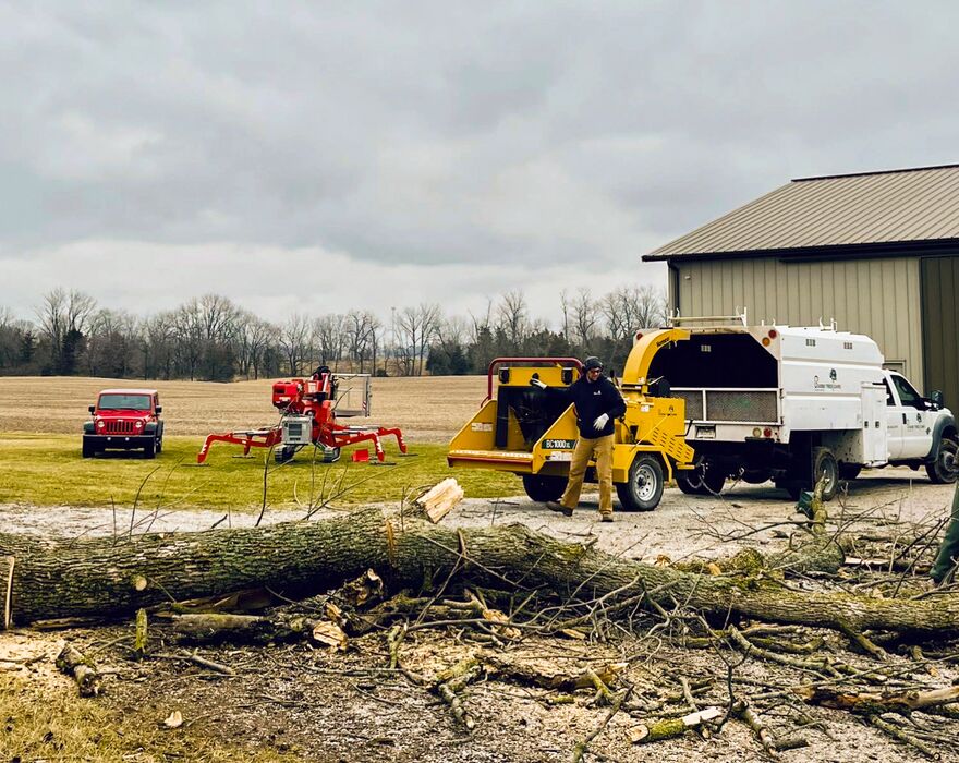 A man stands by a brush chipper at a jobsite