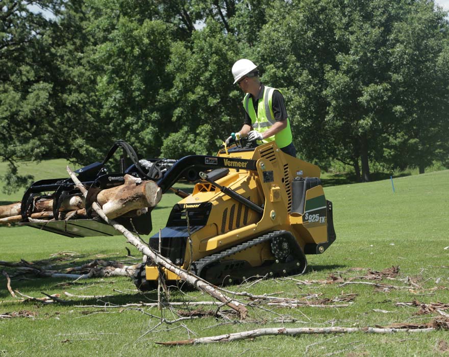 Compact utility loader is being used to clear tree brush