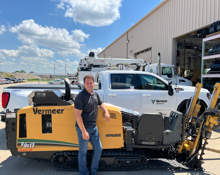 A man stands in front of a horizontal directional drill and a Vermeer midwest pickup truck