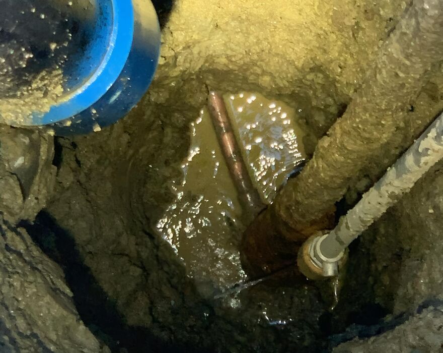 A hole in the ground from vacuum excavation that shows underground utilities