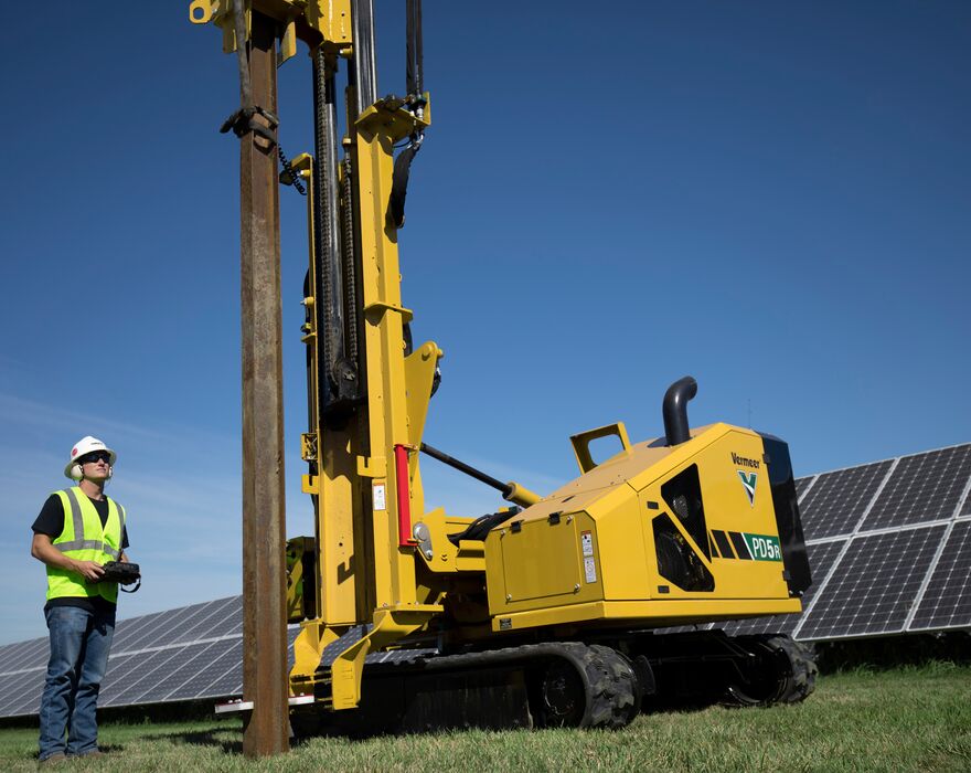 A man stands next to a pile driver while operating it