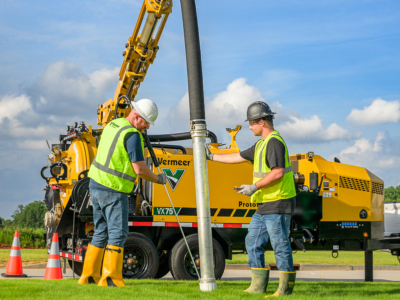 Two men working with a vacuum excavation truck