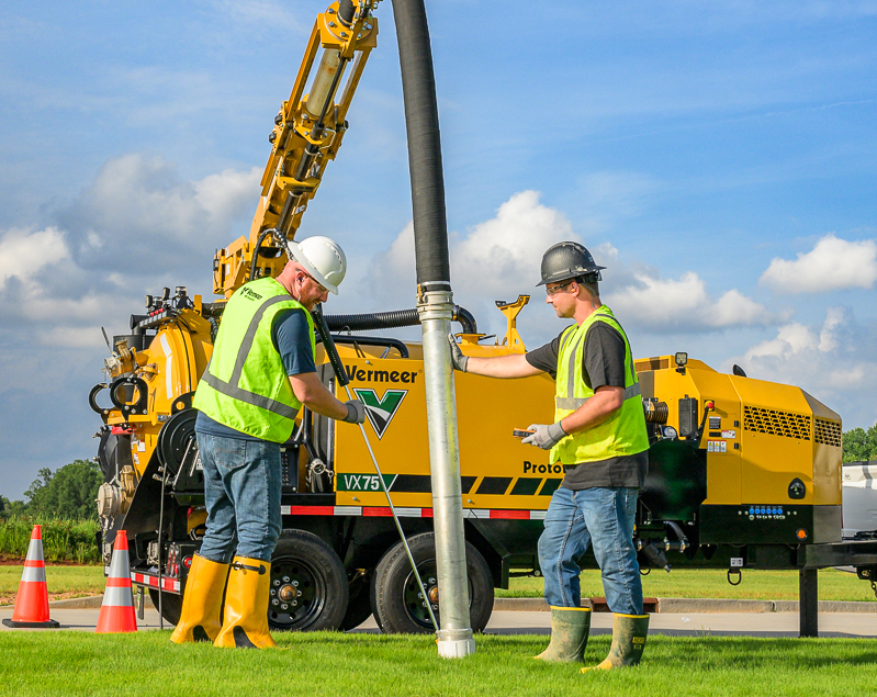 Two men working with a vacuum excavation truck