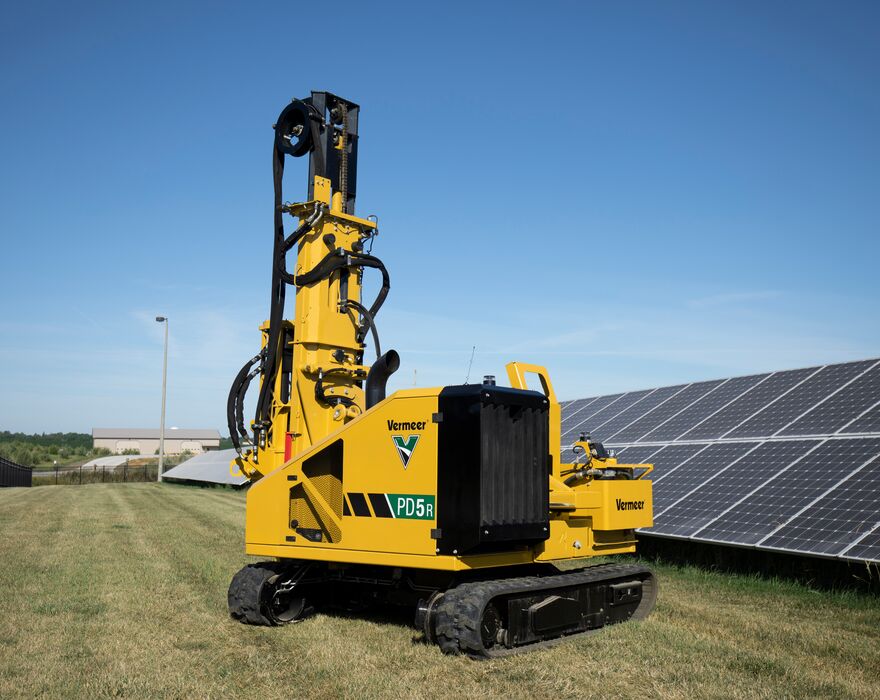 A pile driver sitting in a solar field