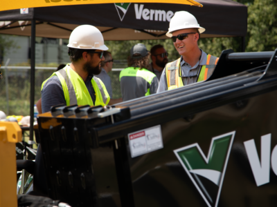 Two men talk behind a horizontal directional drill