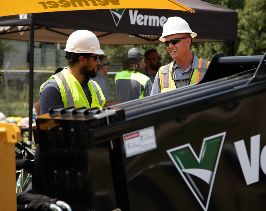 Two men talk behind a horizontal directional drill